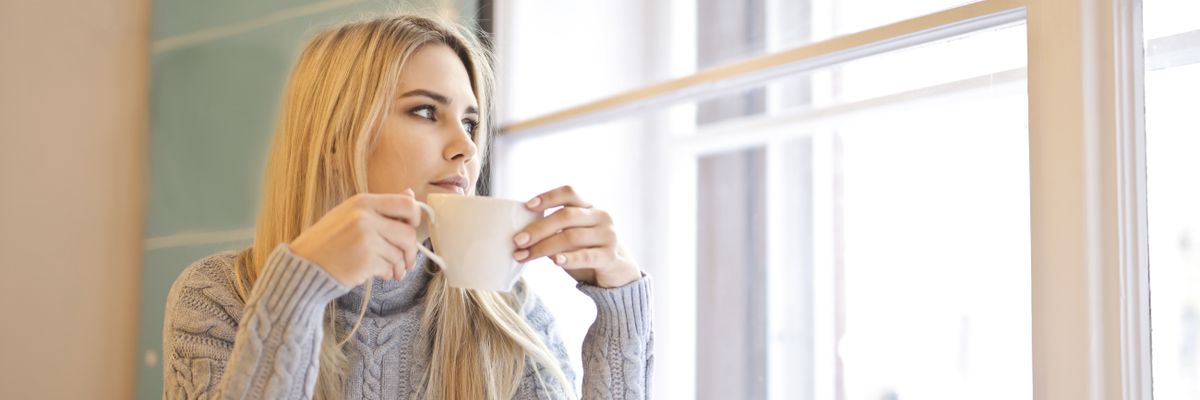 ストレスで疲れた心を休める窓辺でコーヒーを飲む女性