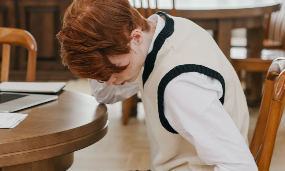 勉強や学校のストレスで限界を感じてうつむく中学生