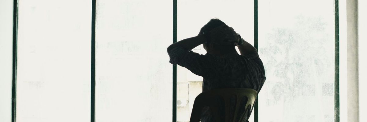 辞めますが言えず一人で頭を抱える男性のシルエット